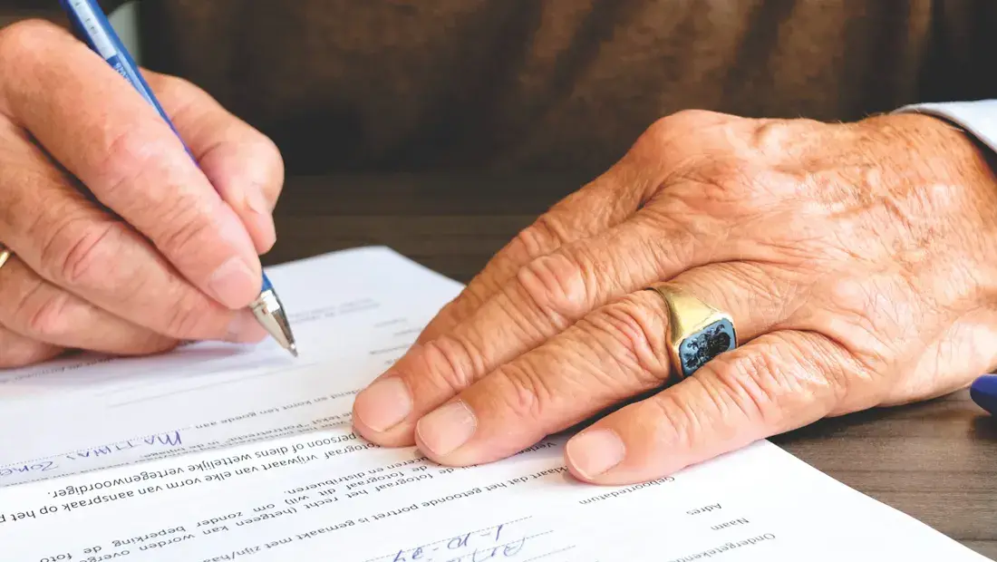 A client signing estate planning documents with a pen